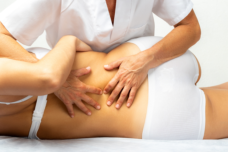 In this image, a therapist is seen assisting a client in a stretching exercise, focusing on the lower back. The therapy session takes place on a blue mat, highlighting a manual therapy technique aimed at relieving lower back pain through hands-on assistance and stretching movements.